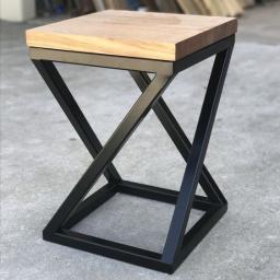 Pracownia Stolarska Willow - Nowoczesny stolik pomocniczy z blatem z jasnego drewna i geometryczną podstawą z czarnego metalu, na szarym betonowym tle.