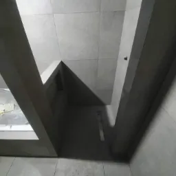 Szara łazienka w trakcie remontu, widok z dołu na sufit i fragment ściany z zamontowanymi płytami karton gips, widoczny odpływ liniowy w podłodze.