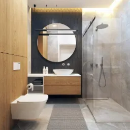 Nowoczesna łazienka z kabiną prysznicową typu walk-in, okrągłym lustrem podświetlanym listwą LED, wiszącą miską WC i szafką z drewnianymi frontami, wykończona szarą płytką imitującą marmur.