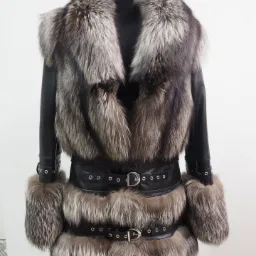 Czarna skórzana kurtka z obszyciem z naturalnego futra srebrno-brązowego lisa, zapinana na dwa skórzane paski z srebrnymi klamrami, prezentowana na manekinie.