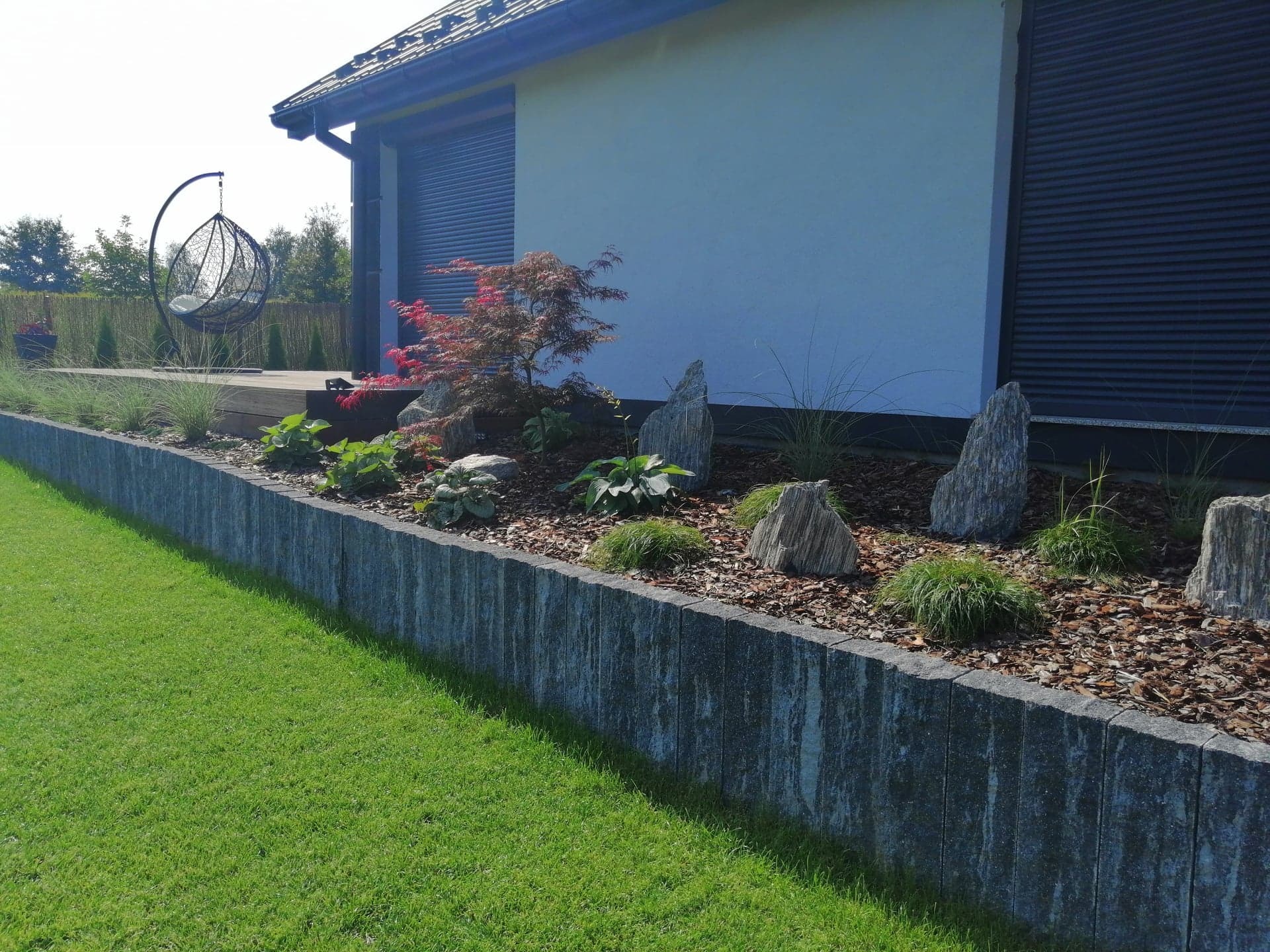 Ułożenie obrzeża z palisady Uni Split , nasadzenia roślinne , montaż systemu nawadniającego oraz trawnik z rolki