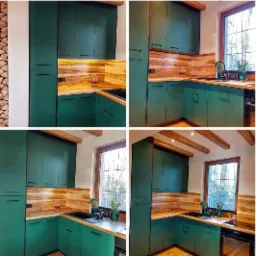 Kompaktowa kuchnia w odcieniach butelkowej zieleni z drewnianym blatem i fornirem, czarny zlew i armatura, drewniane belki stropowe, widok z okna na las.