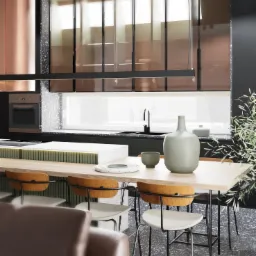 Nowoczesna kuchnia z wyspą, drewnianym stołem i krzesłami w stylu skandynawskim, minimalistyczne dodatki, czarne szafki i podłoga z lastryko.