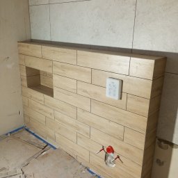 Profesjonalne usługi malarskie i remonty wnętrz. - Obudowa WC z płytek imitujących drewno, z wnęką i przyciskiem spłukiwania. Widoczne rury instalacyjne. Podłoga zabezpieczona kartonem.