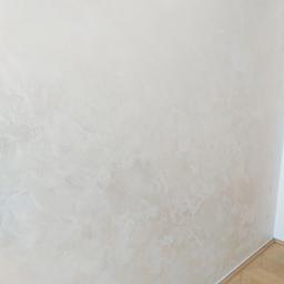 Jacek Zakrzewski - Beżowa ściana z dekoracyjnym efektem malowania, widoczny fragment parkietu w jodełkę przy podłodze.