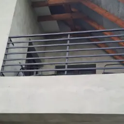 Czarna, pozioma konstrukcja zabezpieczająca balkon z widocznym drewnianym zadaszeniem i fragmentami mebli balkonowych w tle.