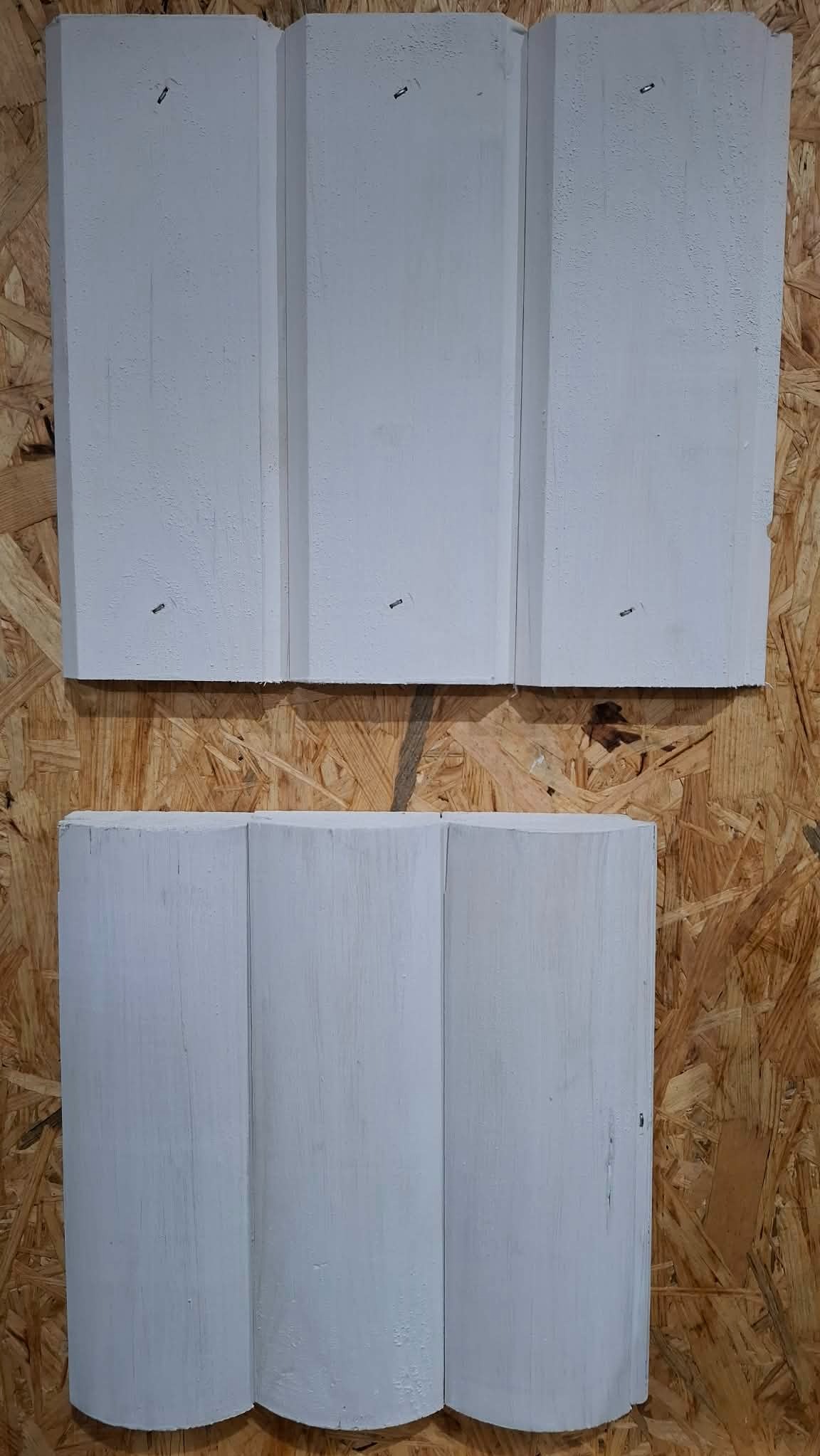 Dwa rodzaje białych, drewnianych paneli ściennych: górny z prostymi krawędziami, dolny z zaokrąglonymi, na tle płyty OSB. Prezentacja wzorów.