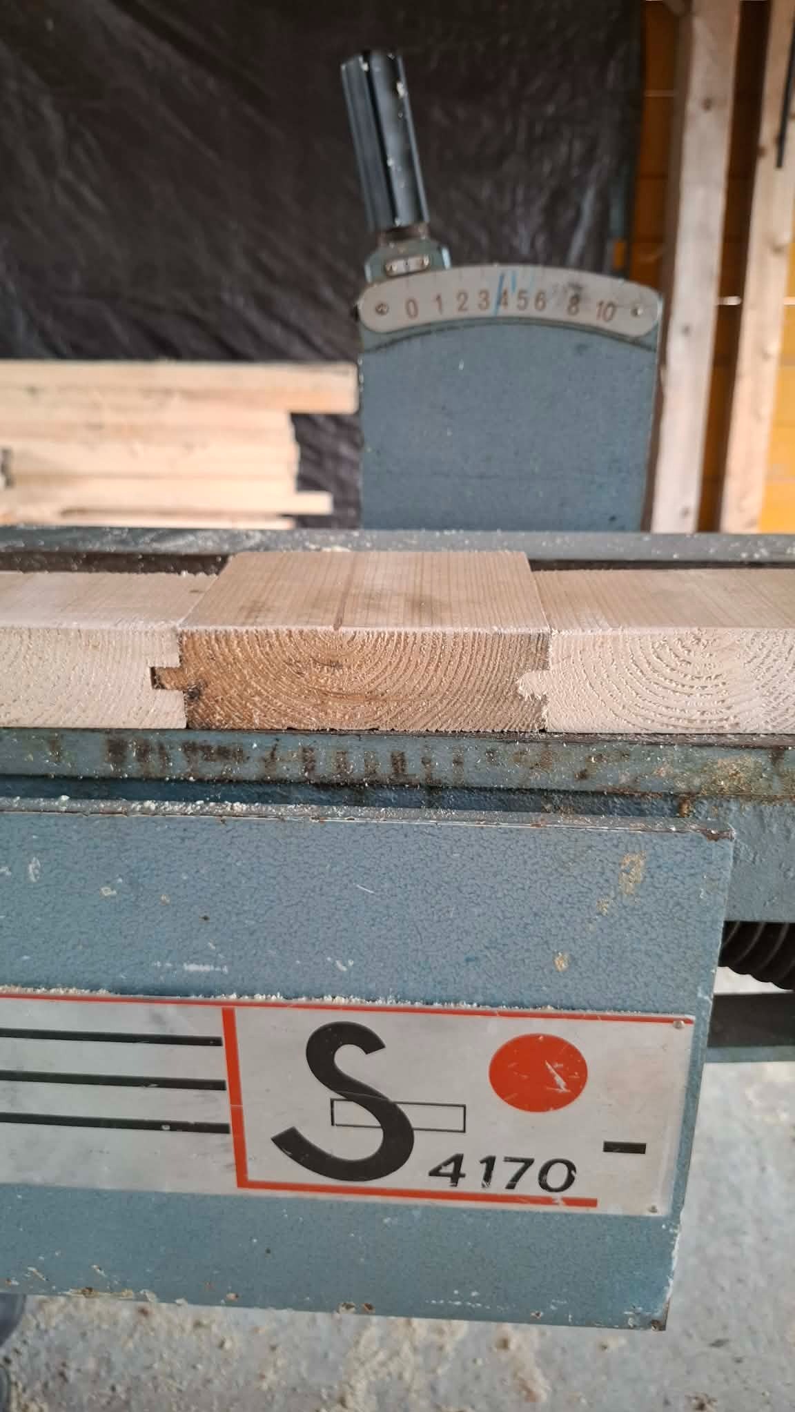 Frezowanie drewna na maszynie stolarskiej, widoczne połączenie na wpust i wypust. Detal obróbki drewna, zbliżenie na proces łączenia elementów.