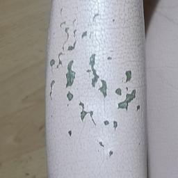 Clean Tom - Podłokietnik fotela obity jasnoróżową skórą ekologiczną z widocznymi pęknięciami i odpryskami farby, wykończony ozdobnymi srebrnymi ćwiekami.