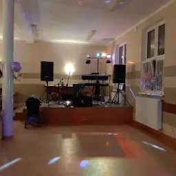 Przygotowana scena z instrumentami, nagłośnieniem i oświetleniem w sali z dekoracjami świetlnymi na suficie, gotowa na występ.