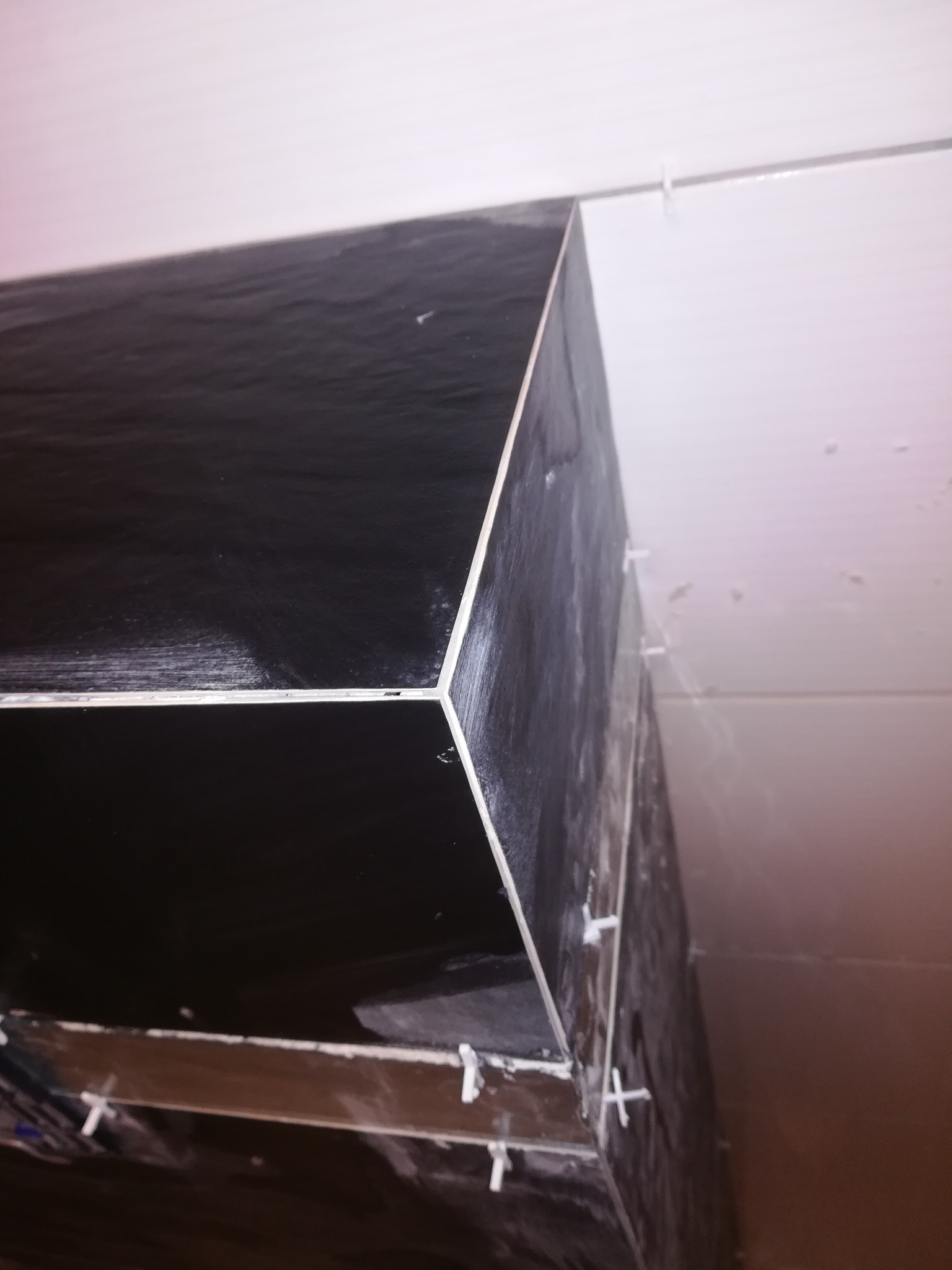 Układanie ciemnych, błyszczących płytek na obudowie, widoczne krzyżyki dystansowe, krawędzie wykończone z precyzją.