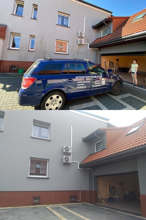 Dwukondygnacyjny budynek z szarą elewacją, widoczne dwa klimatyzatory na ścianie, zaparkowany niebieski samochód z napisem 'Wysokościowe mycie' oraz otwarta brama garażowa, w tle kobieta.