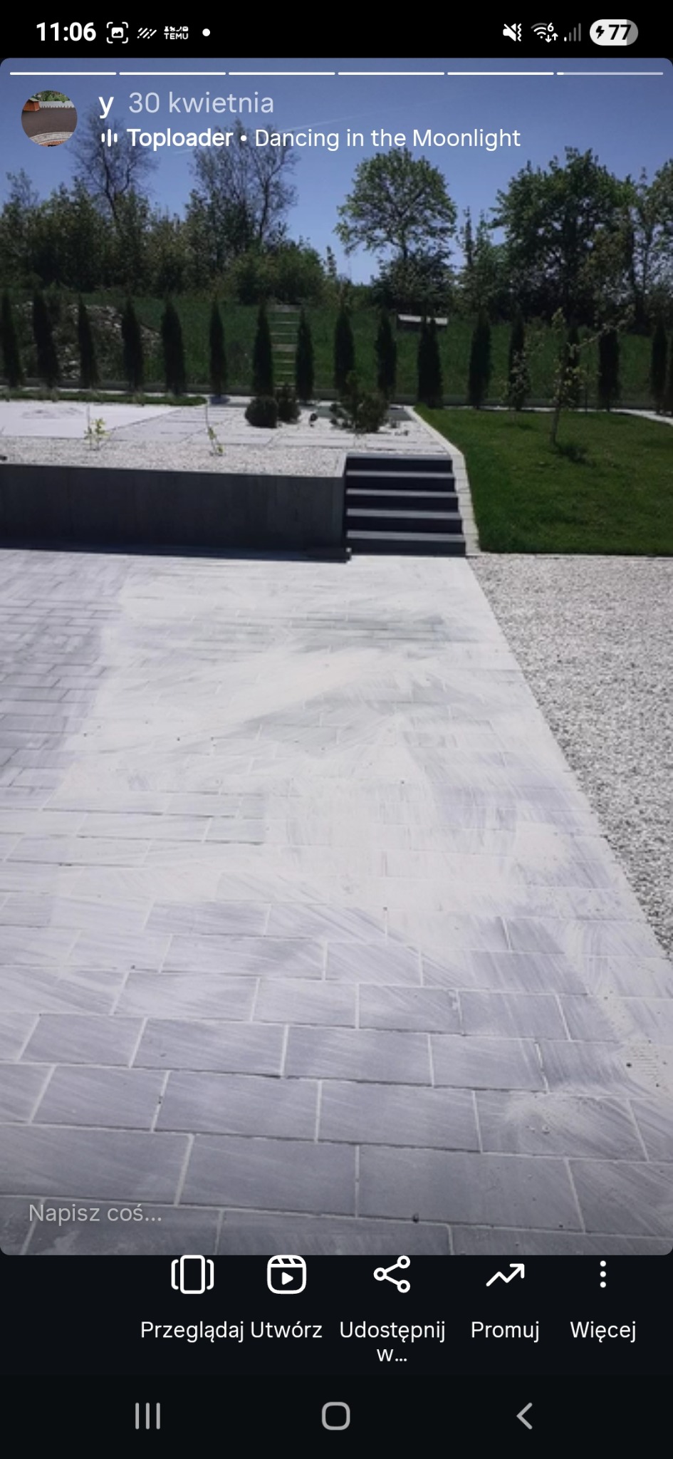 Nowoczesny ogród z szarą kostką brukową, schodami i białym żwirem. W tle rząd tuj i trawnik. Minimalistyczny design z elementami zieleni.