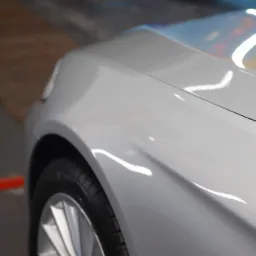 Fragment karoserii srebrnego samochodu po umyciu z widocznymi odbiciami światła, koło z aluminiową felgą, Białystok.