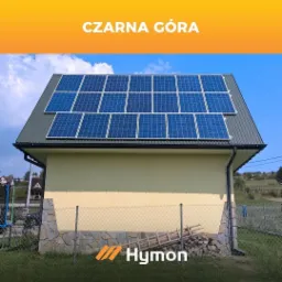 Dom jednorodzinny z panelami słonecznymi na dachu, widoczne logo firmy Hymoń na ogrodzeniu.