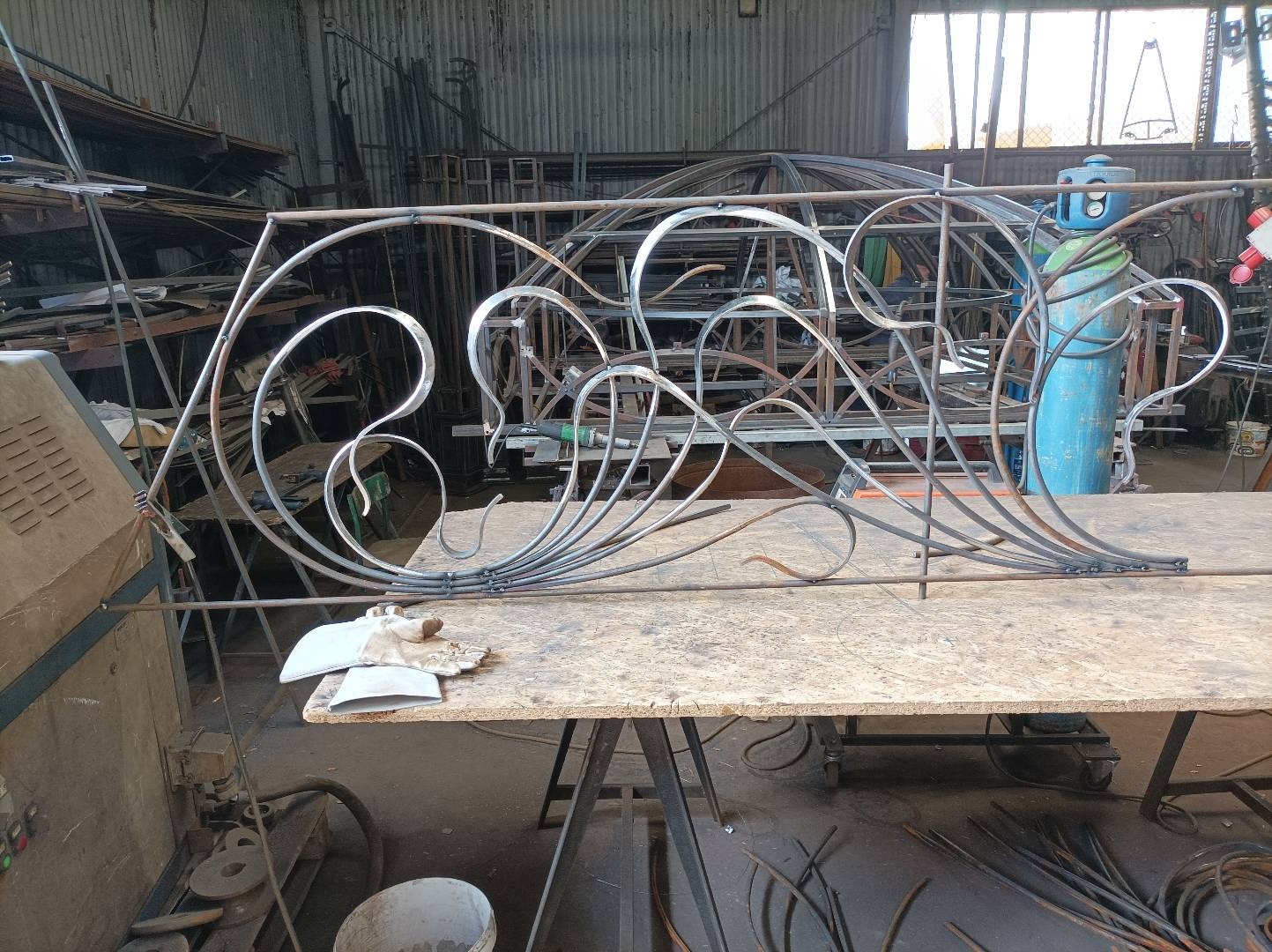 Wykonywany w Lubrańcu element dekoracyjny z metalu o fantazyjnych kształtach, prawdopodobnie fragment większej konstrukcji, widoczny na tle warsztatu.