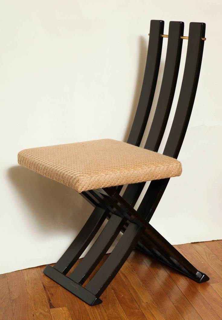 Składane krzesło z czarnego drewna z siedziskiem z plecionki, widoczne na parkiecie, minimalistyczny design.