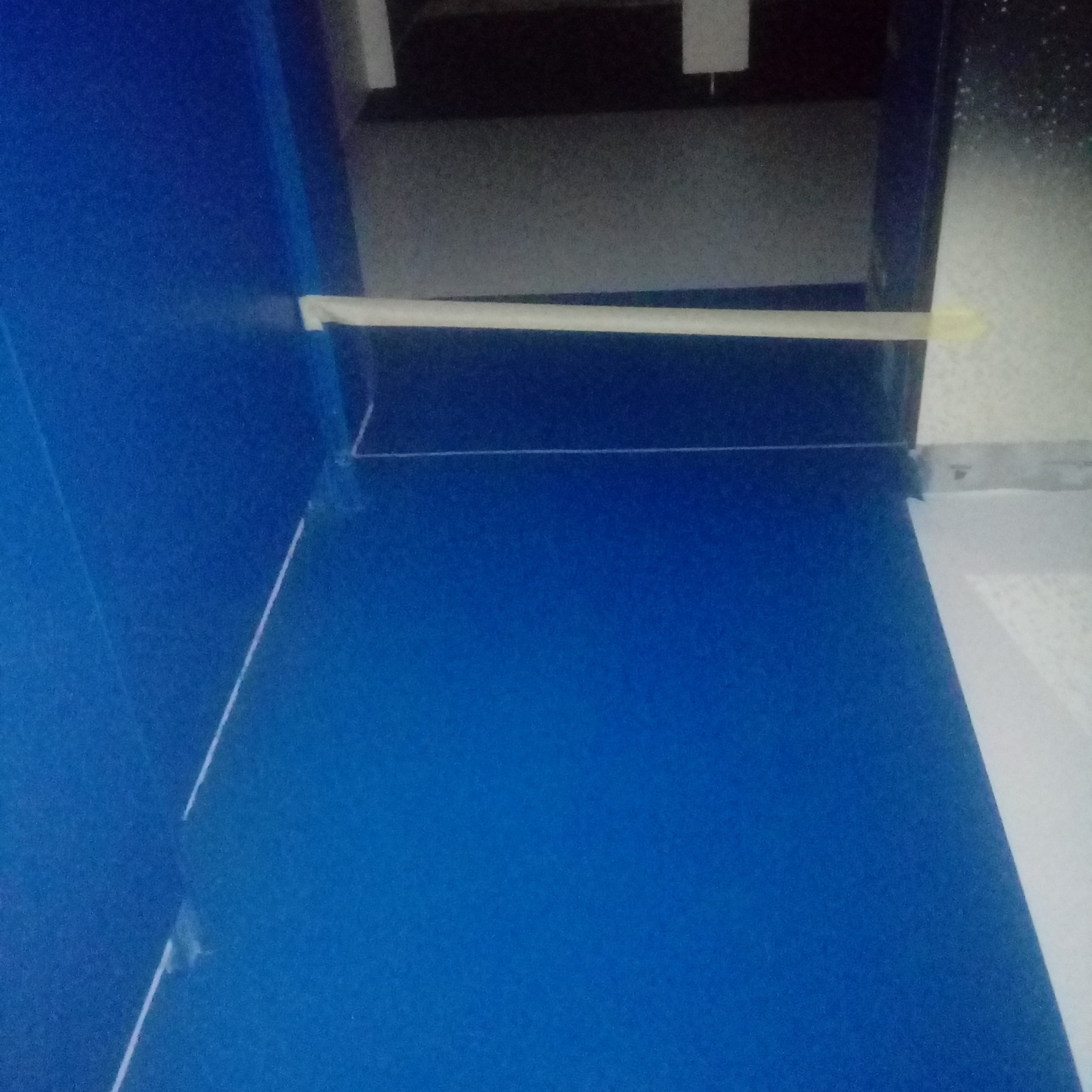 Niebieska powierzchnia z widocznym sznurkiem wyznaczającym linię i poziomnicą przymocowaną taśmą, przygotowanie do wylewki.