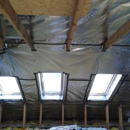 Onsetbud Zhanna Slyvka - Poddasze z ociepleniem z folii aluminiowej i trzema oknami dachowymi, widoczne drewniane belki konstrukcyjne i drabina.