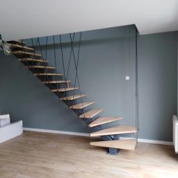 Onsetbud Zhanna Slyvka - Nowoczesne schody drewniane z metalową konstrukcją na tle szarej ściany i jasnej podłogi laminowanej.