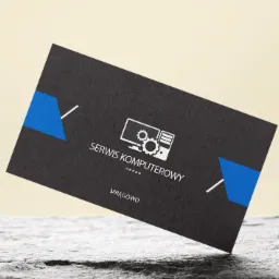 Czarna wizytówka z niebieskimi akcentami i białym logo przedstawiającym komputer z kołami zębatymi, leżąca na szarej, teksturowanej powierzchni.