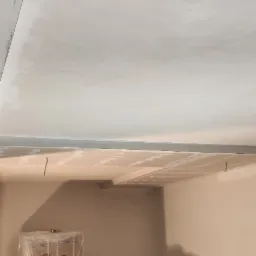 Sufit podwieszany z płyt gipsowo-kartonowych w trakcie montażu, widoczne profile i przewody elektryczne wystające z sufitu.