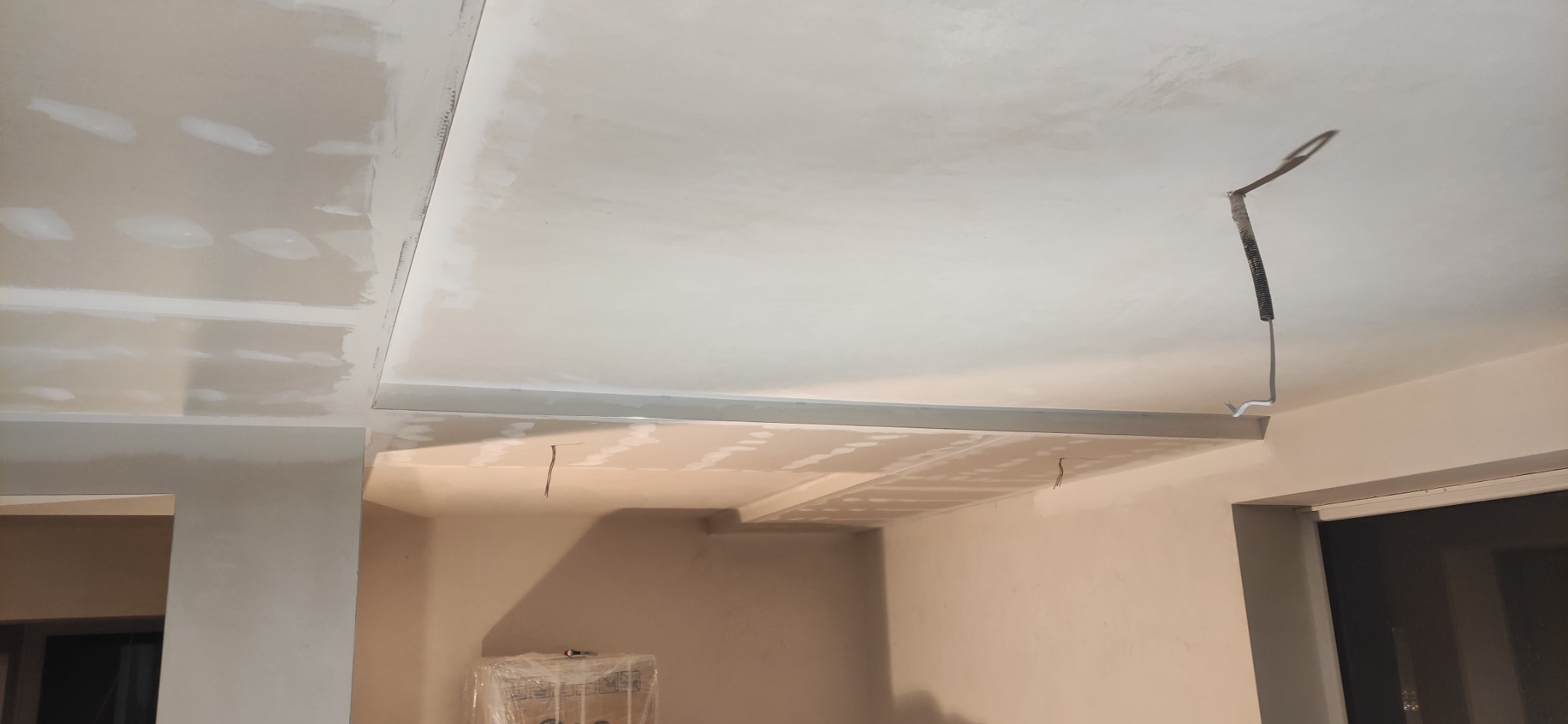 Sufit podwieszany z płyt gipsowo-kartonowych w trakcie montażu, widoczne profile i przewody elektryczne wystające z sufitu.