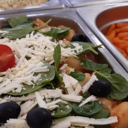 InGastro Kamil Polinceusz - Bufet cateringowy: sałatka z pomidorkami cherry, oliwkami, szpinakiem i serem feta w sosie pomidorowym, obok marchewki baby.