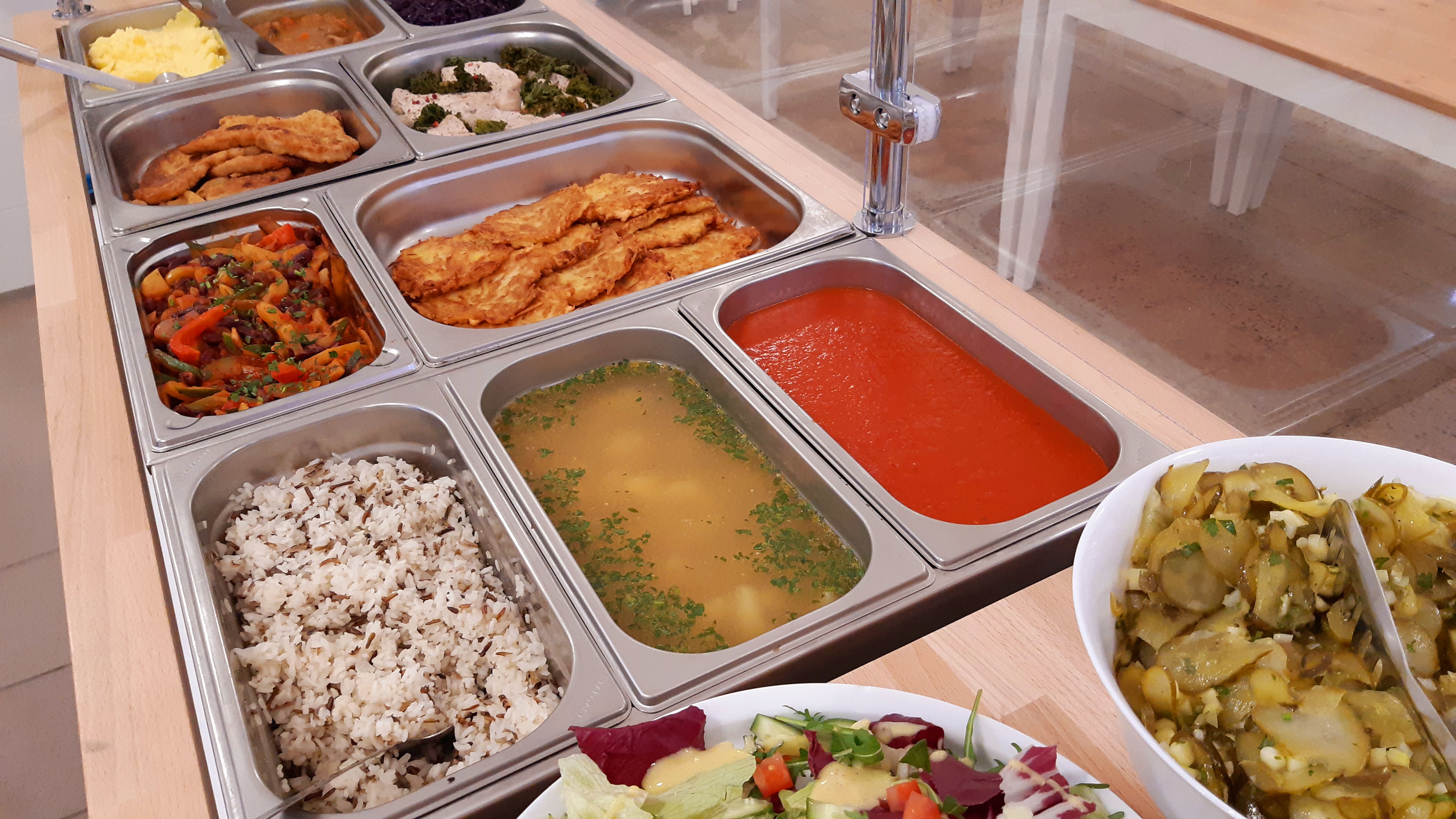 Bufet z różnorodnymi daniami: puree ziemniaczane, kotlety, leczo, placki ziemniaczane, sałatka z kurczakiem, ryż z dzikim ryżem, zupa z pietruszką, sos pomidorowy, sałatka ziemniaczana i sałatka...