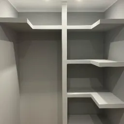 Wnęka z półkami z płyty karton gips, szpachlowana i pomalowana na szaro, z widocznymi dwoma punktowymi źródłami światła w suficie.