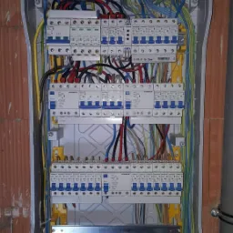 Rozdzielnica elektryczna z zamontowanymi bezpiecznikami i okablowaniem w trakcie instalacji w Radomiu, widoczne przewody w różnych kolorach i elementy montażowe.