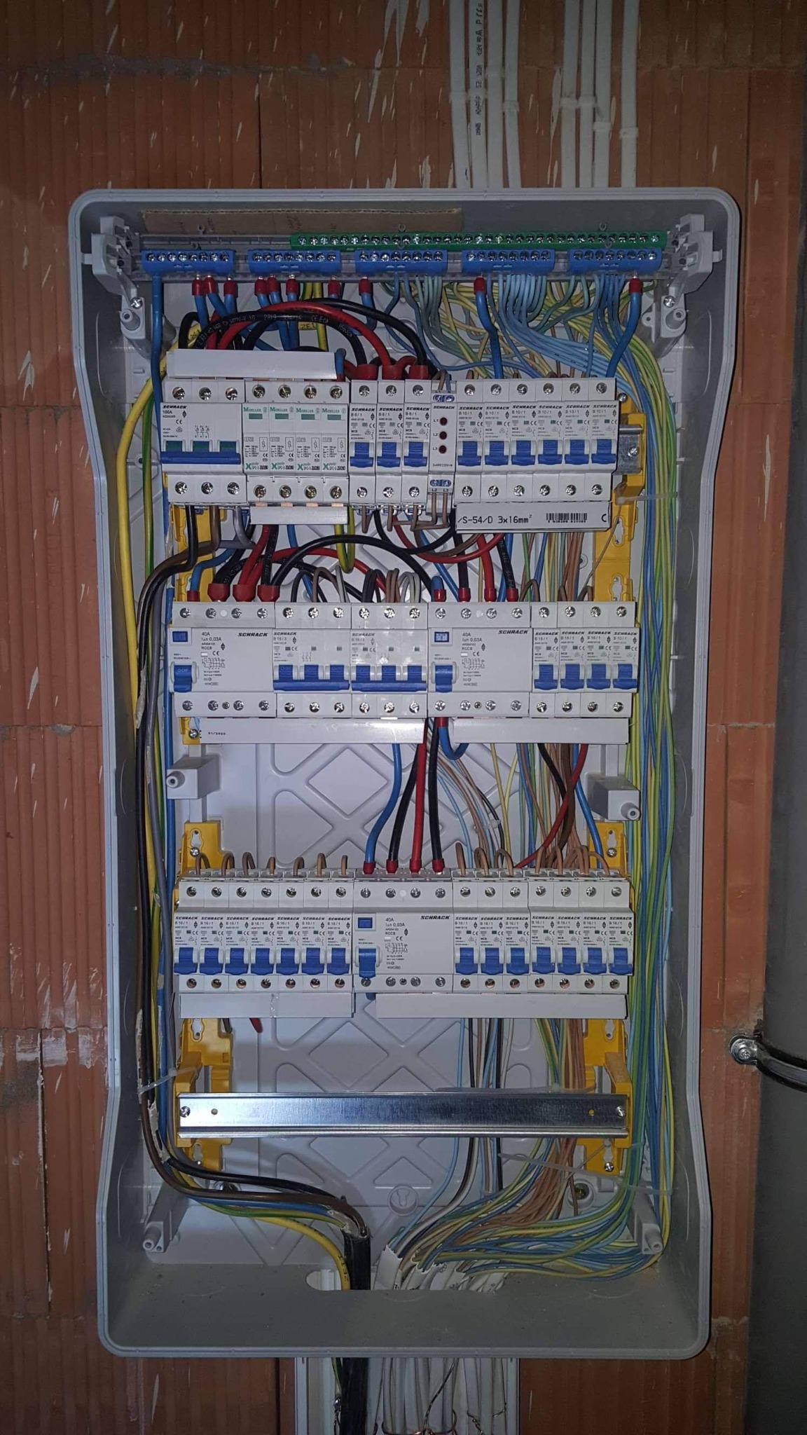 Rozdzielnica elektryczna z zamontowanymi bezpiecznikami i okablowaniem w trakcie instalacji w Radomiu, widoczne przewody w różnych kolorach i elementy montażowe.