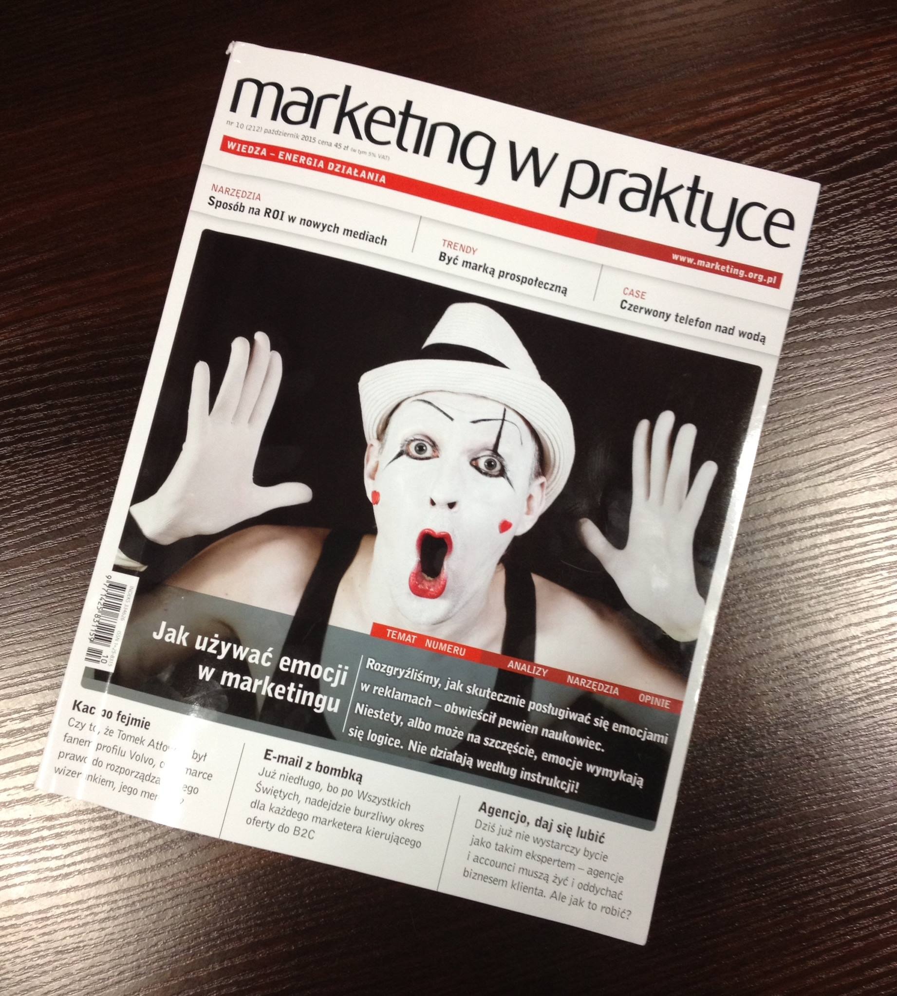 Okładka magazynu 'Marketing w Praktyce' z ilustracją mimu z otwartymi ustami i białymi rękawiczkami, na ciemnym drewnianym tle.