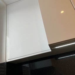 MNW PW FL STUDIO - Białe, lakierowane fronty szafek kuchennych z oświetleniem LED podszafkowym i czarnym blatem z połyskiem. Minimalistyczny design.