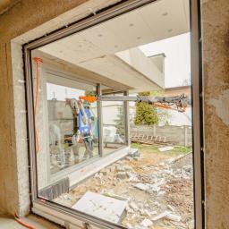 Hastam - Montaż okna panoramicznego za pomocą specjalistycznego podnośnika próżniowego w surowym stanie budynku.