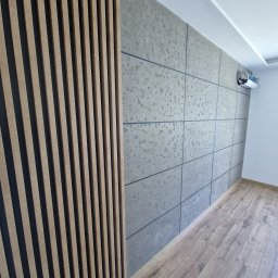 FIRMA HANDLOWO - USŁUGOWA Marcin Grabowski - Nowoczesne wnętrze z panelami ściennymi imitującymi beton, drewnianymi lamelami dekoracyjnymi, jasną podłogą i klimatyzatorem na ścianie.