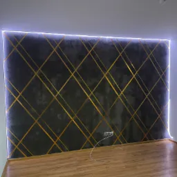 Ściana z dekoracyjnym tynkiem w odcieniach szarości, z geometrycznym wzorem ze złotych pasków i podświetleniem LED w Radomiu.
