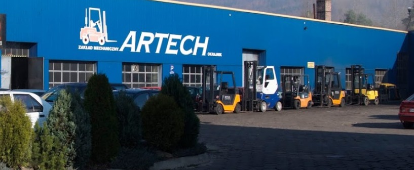 Błękitny budynek z logo firmy ARTECH i rzędem wózków widłowych różnych kolorów zaparkowanych przed nim.