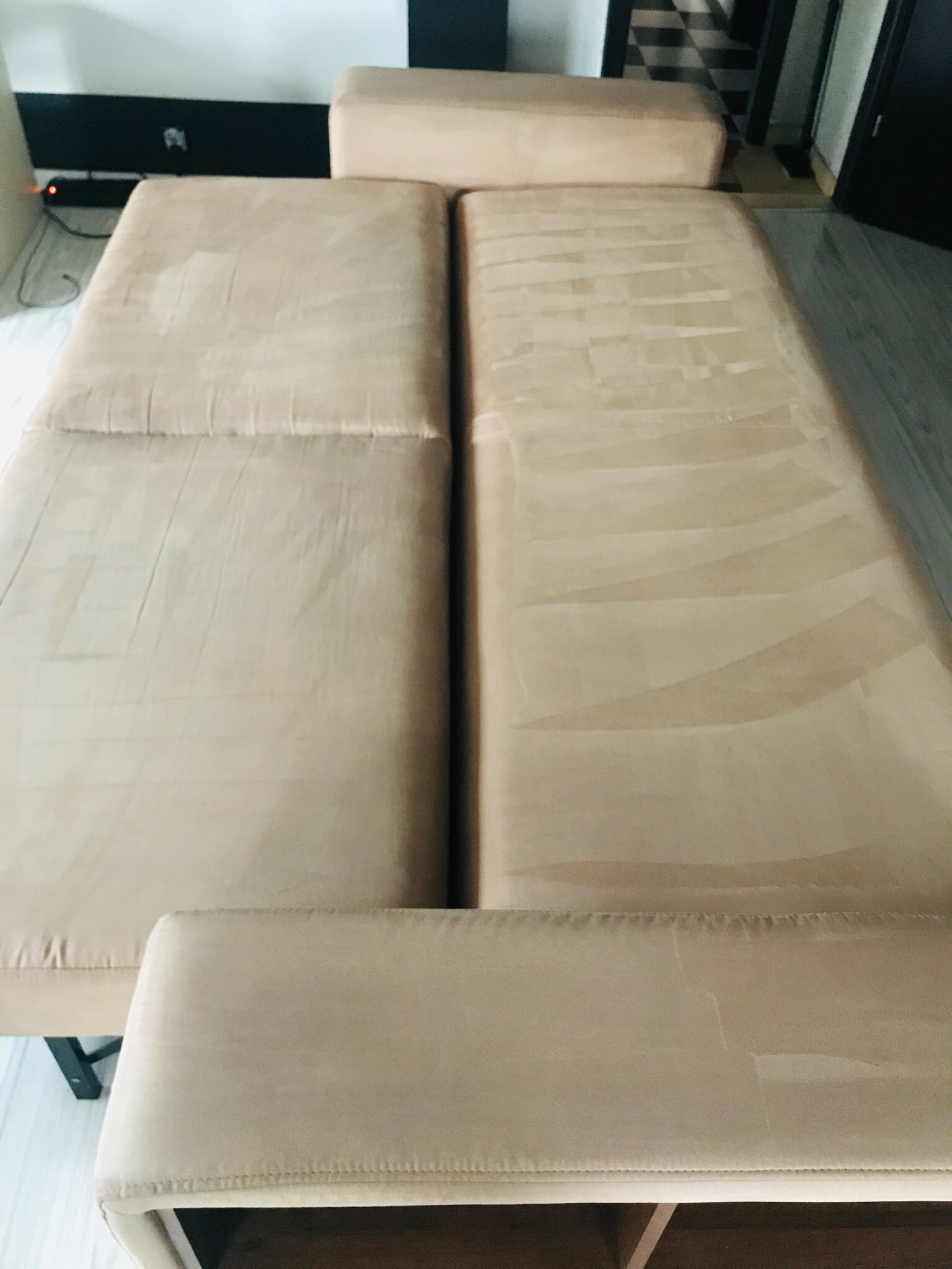 Beżowa kanapa modułowa z widocznymi śladami po czyszczeniu, wskazującymi na różnicę w odcieniu między wyczyszczoną a niewyczyszczoną częścią tapicerki.