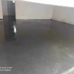 Świeżo wylana, gładka, szara posadzka w surowym pomieszczeniu z białymi ścianami, widoczne ślady po szpachli.