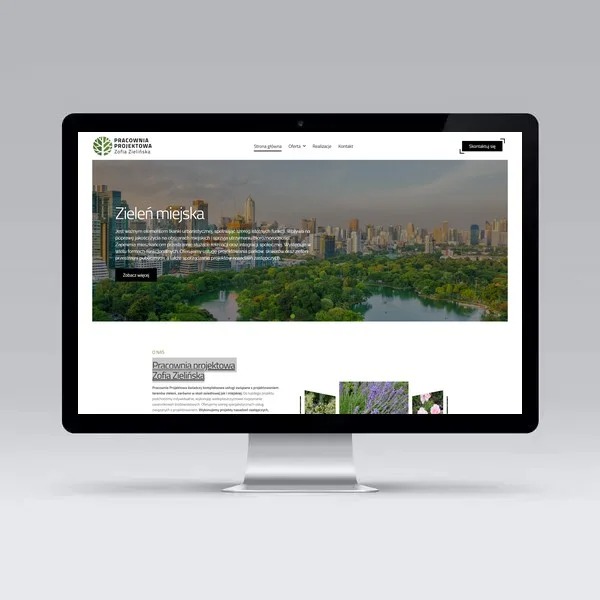Monitor wyświetla stronę internetową pracowni projektowej z motywem zieleni miejskiej i panoramą miasta w tle, widoczny pasek menu i logo firmy w lewym górnym rogu.