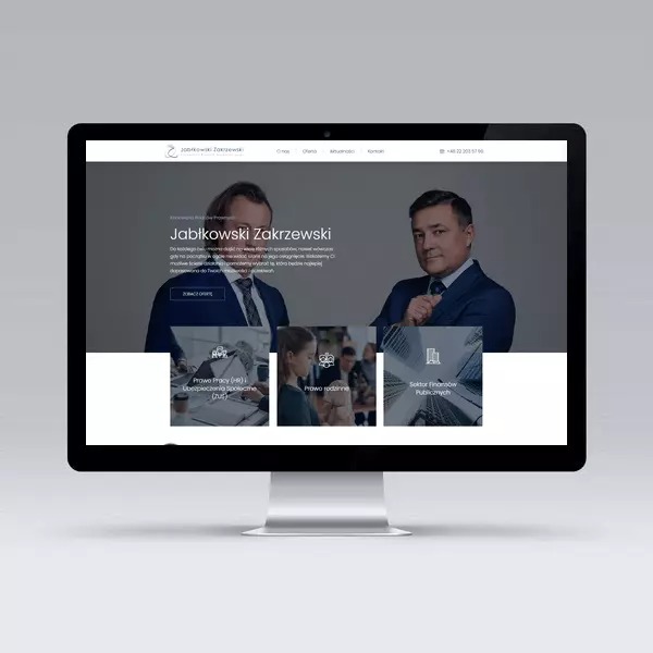 Monitor iMac wyświetlający stronę internetową kancelarii prawnej Jabłkowski Zakrzewski z dwoma prawnikami w garniturach i sekcjami tematycznymi: Prawo Pracy, Prawo Rodzinne, Sektor Finansów...