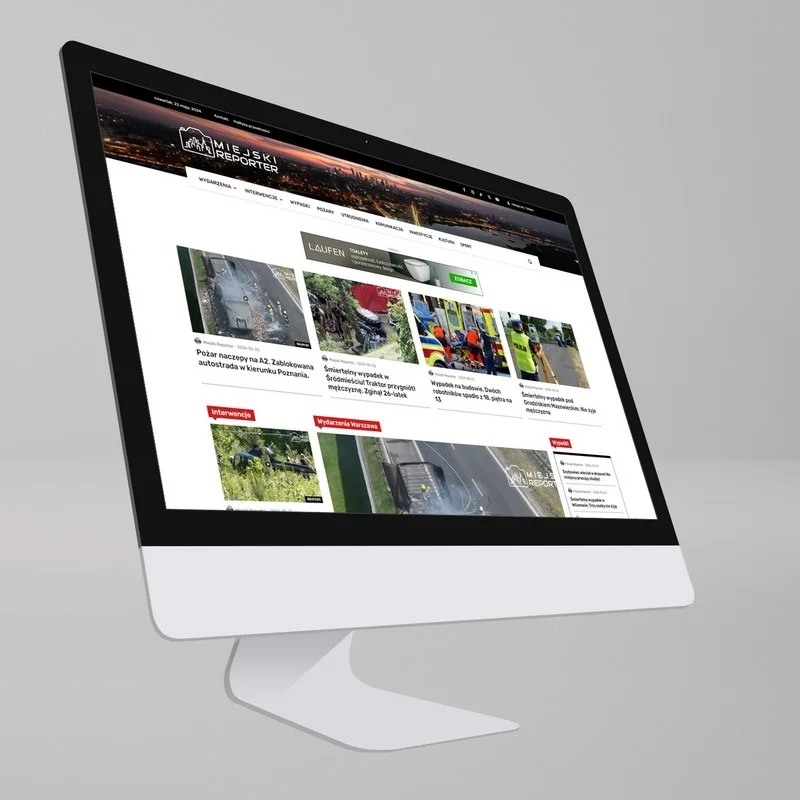 Monitor wyświetlający stronę internetową Miejski Reporter z nagłówkiem z panoramą miasta nocą i aktualnościami o wypadkach i interwencjach