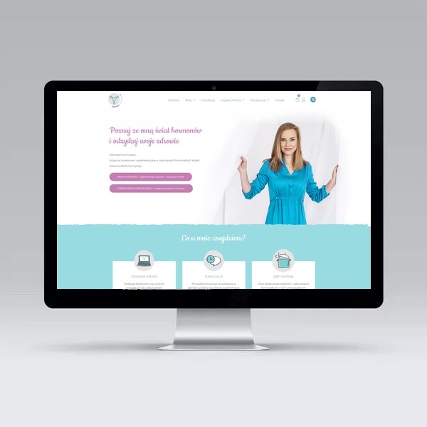 Monitor wyświetlający stronę internetową z blondynką w turkusowej sukience na tle białych zasłon, strona w pastelowych kolorach z motywami zdrowia i odżywiania.