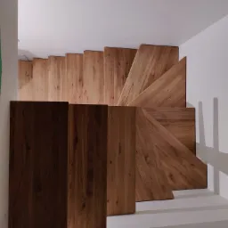 Nowoczesne schody drewniane z ciemnym drewnem na pierwszym planie, widok z góry, minimalistyczne wnętrze.