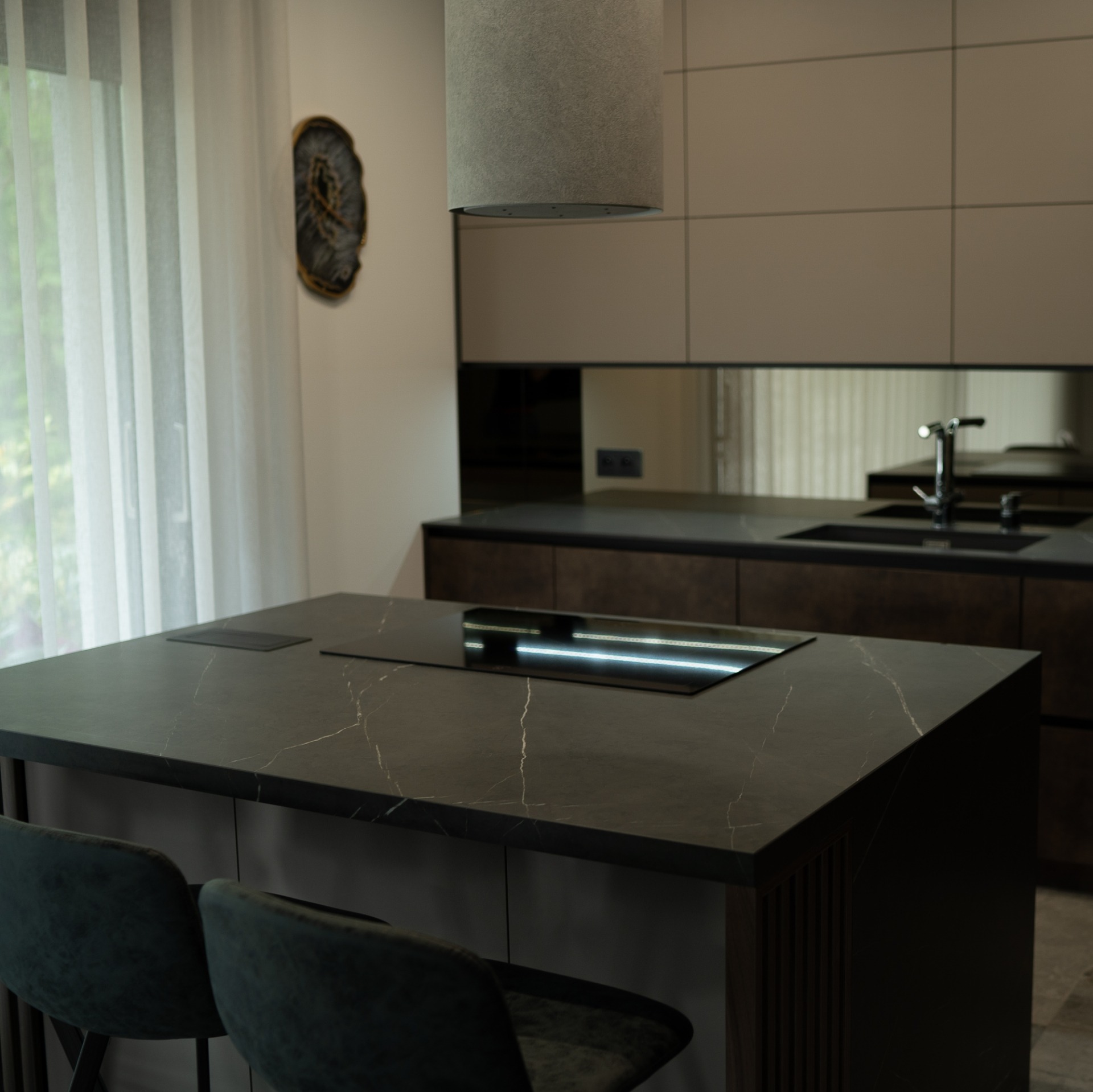 Ciemny blat kuchenny z marmurkowym wzorem i wbudowaną płytą indukcyjną, widok na nowoczesną kuchnię z beżowymi szafkami i okrągłą dekoracją ścienną.