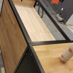 Konstrukcja schodów z metalową ramą i drewnianymi stopniami w trakcie montażu, widoczna piła do metalu i elementy mocujące w tle.