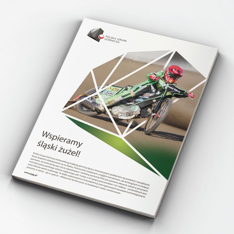 Katalog firmowy Polskiej Grupy Górniczej z motywem żużlowym, przedstawiający zawodnika na motocyklu podczas wyścigu, z hasłem 'Wspieramy śląski żużel!'