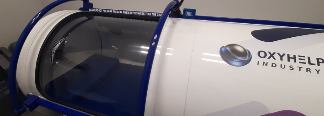 Komora hiperbaryczna Oxyhelp Industry z widocznym wnętrzem i napisem ostrzegawczym nad uszczelką.