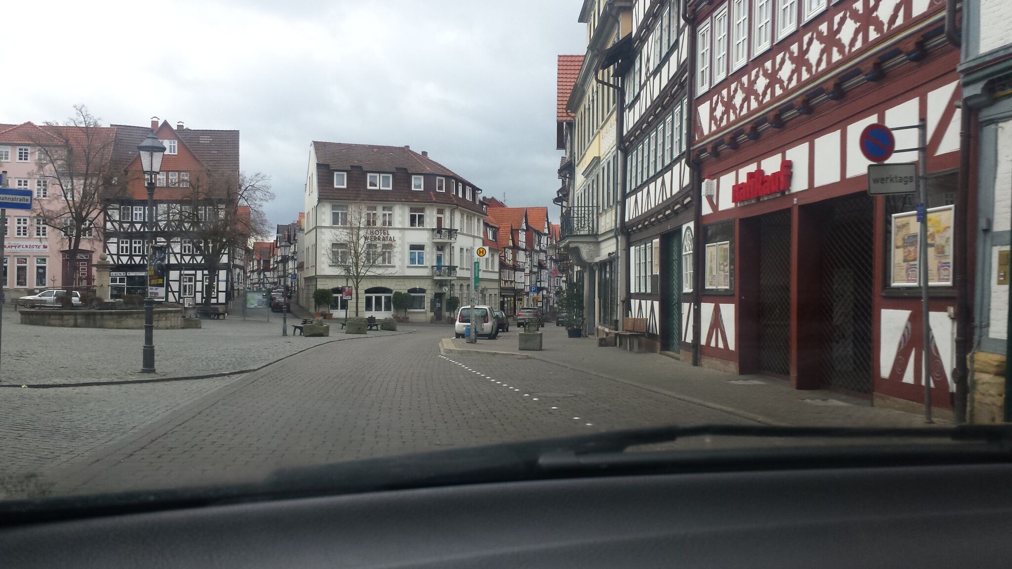 Widok z wnętrza pojazdu na ulicę w niemieckim mieście z charakterystyczną zabudową szachulcową w pochmurny dzień.